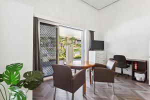 - un salon avec une table, des chaises et un bureau dans l'établissement Stroll To Fremantle's Core Studio Apartment, à Fremantle