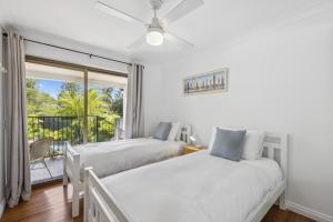 two beds in a bedroom with a balcony at Diggers Beach Surf House in Coffs Harbour