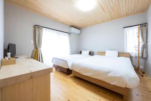 a bedroom with two beds and a desk and window at Hinoki house in Fukuoka