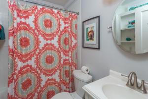 La salle de bains est pourvue d'un rideau de douche rouge et de toilettes. dans l'établissement Sammy's Cottage, à Île de Saint-Simon