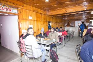 a group of people sitting at a table in a restaurant at Utsav in Manāli