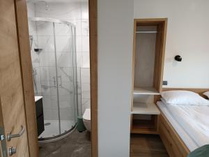 a bathroom with a shower and a bed in a room at Apartmaji Hodak in Bohinj