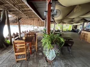 a restaurant with tables and chairs and a plant at Apsara & Dragon’s Supra Wellness Resort in Baan Tai