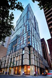 雪梨的住宿－Meriton Suites Sussex Street, Sydney，一座高大的玻璃建筑,前面的人在步行
