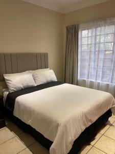 Schlafzimmer mit einem großen weißen Bett und einem Fenster in der Unterkunft Thorntree Self Catering Apartment, Witbank in Witbank