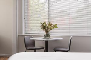 a table with chairs and a vase of flowers on it at MAC St Kilda by Melbourne Apartment Collection in Melbourne