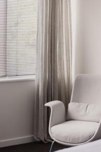 a white chair sitting in front of a window at MAC St Kilda by Melbourne Apartment Collection in Melbourne