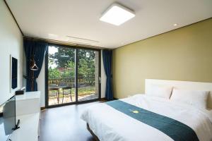 um quarto com uma cama, uma televisão e uma janela em Misoga Pension em Seogwipo