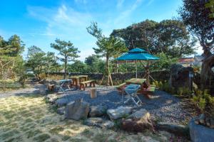 um pátio com um guarda-sol, uma mesa e cadeiras em Misoga Pension em Seogwipo