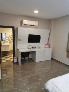 1 dormitorio con escritorio, TV y cama en Marina Town, en Sohar