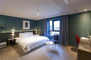 a bedroom with a white bed and a green wall at Brown Dot Hotel Hadan in Busan