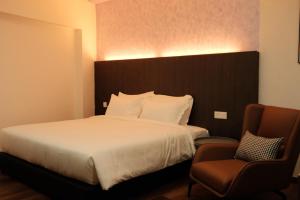 a hotel room with a bed and a chair at UniHome Suite in Bintulu
