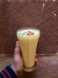 a person holding up a glass of orange juice at Shahi Guest House in Jodhpur