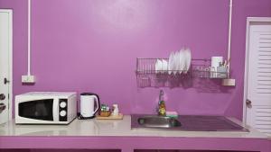 a purple kitchen with a sink and a microwave at Hello House in Krabi