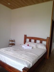 1 cama con sábanas blancas y cabecero de madera en Vulkan Arenal Amazing View Lodge 4 WD, en El Castillo de la Fortuna