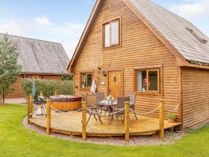 Ce chalet en bois dispose d'une terrasse et d'une table. dans l'établissement 3 Bed in Ledbury 77378, 