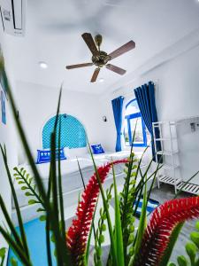 1 dormitorio con ventilador de techo y flores rojas en Dragon Sea Homestay, en Hoi An