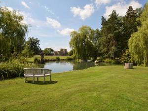a park bench sitting in the grass near a pond at 2 Bed in Sherborne FOLKI in Long Burton