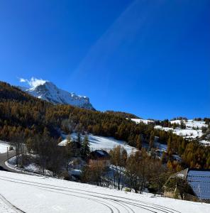 a snowy road with a mountain in the background at Home Sweet Sauze - Chaleureux appartement - Lumineux et calme - Vue sur la montagne in Enchastrayes +3 photos