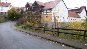 eine Straße vor einem Haus mit einem Zaun in der Unterkunft Bauernhofpension Büchsenschütz in Harbshausen