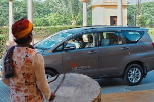 a woman walking past a car with a surfboard at Jaisalmer Marriott Resort & Spa in Jaisalmer