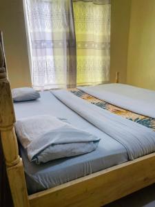 two twin beds in a bedroom with a window at Ignite guest and apartment in Rubavu