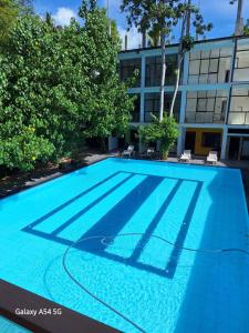 a large blue swimming pool in front of a building at Jagabay Resort & Surfing School in Weligama