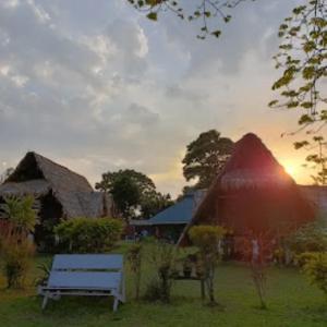 a bench in front of a building with the sun setting at Namdapha Jungle Camp Miao 