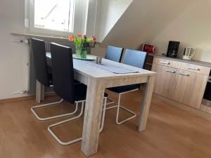 a wooden table with black chairs and a kitchen at Ferienwohnung Seerose in Hemfurth-Edersee