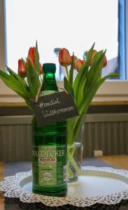 a green bottle on a table with a vase of flowers at Ferienwohnung Seerose in Hemfurth-Edersee