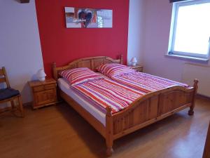 a bed in a bedroom with a red wall at Ferienwohnung "Zum Alten Römer" in Kleinern