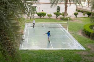 two people playing tennis on a tennis court at Muscat Oasis Residences in Muscat