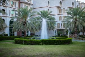 a fountain in front of a building with palm trees at Muscat Oasis Residences in Muscat