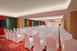 una sala de conferencias vacía con sillas blancas y una pantalla en Fortune Park Tiruppur- Member ITC's hotel group, en Tirupur
