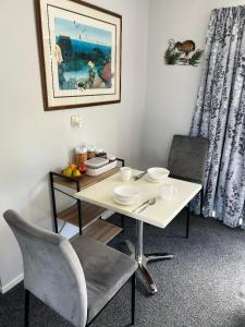 a white table with two chairs and a table with plates at Taipa Views Bed & Breakfast in Kaitaia