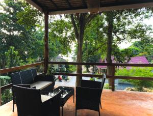 a porch with a table and chairs and trees at Ocean Vibes in Thongsala