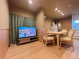een eetkamer met een tafel en een televisie bij ～Fushimi Inari～露天風呂付の一棟貸切のゲストハウス in Kyoto