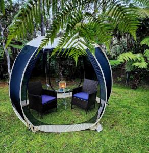 un cenador con sillas y una mesa. en Romantic Retreat, Pop up Dome at your own private yard, Outdoor shower, firepit, 5 min to Hawaii Volcano park, en Volcano