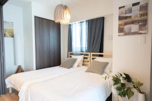 2 camas en un dormitorio con sábanas blancas en 琢居．日暮里布里斯托酒店 Nippori Bristol Hotel, en Tokio