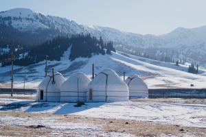 a group of domes in the snow with mountains in the background at Karkyra Yurt Glamping in Sarytëbë
