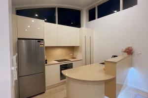 a kitchen with white cabinets and a stainless steel refrigerator at Whitewater Beach House in Old Bar