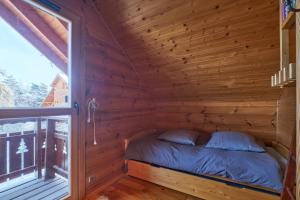 ル・デヴォリュイにあるLe chalet Virginieの窓付きの木造キャビンのベッド1台分です。