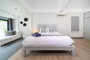 a white bedroom with a large bed and a couch at Sanook Villas -Geng Mak Nai Harn in Rawai Beach