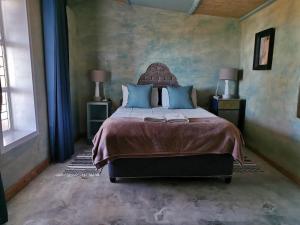 a bedroom with a large bed with blue pillows at Silwerkaroo Gastehuis in Beaufort West