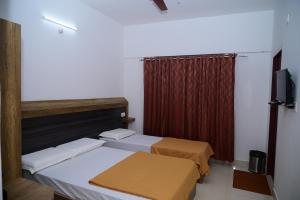 Habitación con 2 camas y cortina roja. en B Six Hotel en Bangalore