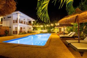 a swimming pool with chairs and umbrellas at night at Dolce Amore Resort in Siquijor