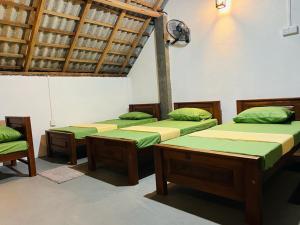 a room with four beds with green and yellow sheets at Bay Vista-Yala in Kirinda