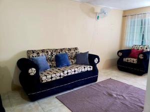 a living room with a black couch and blue pillows at 3bedrm, 2 bthrm. 7East Greater Portmore in Portmore