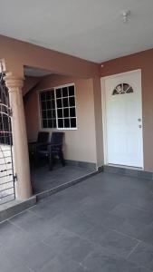 a porch with a white door and a table at 3bedrm, 2 bthrm. 7East Greater Portmore in Portmore