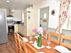 a kitchen and dining room with a wooden table with flowers at 3 Bed in Ledbury 77379 